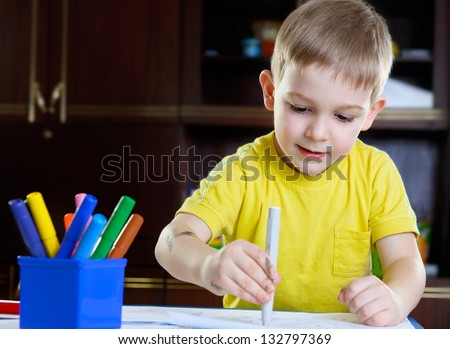 Cute little boy drawing with felt-tip pen at home