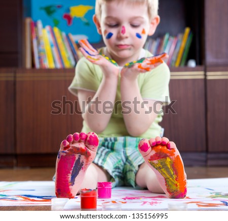 Cute happy boy with colorful  painted hands and foot