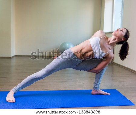 Pretty young woman doing yoga exercise on mat