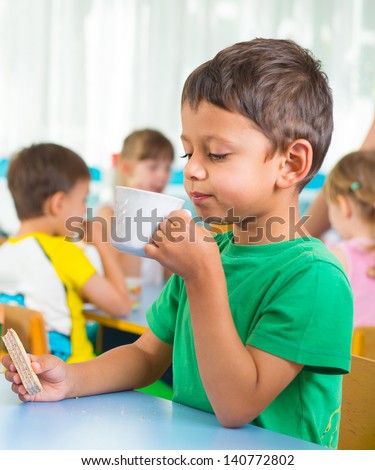 Cute little child drinking milk at kindergarten