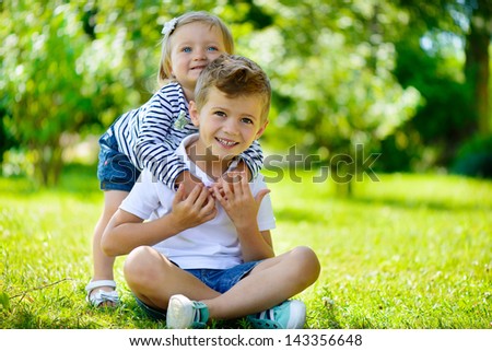 Happy sister and brother together in park during summer day