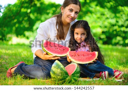Happy indian family eating watermelon in park