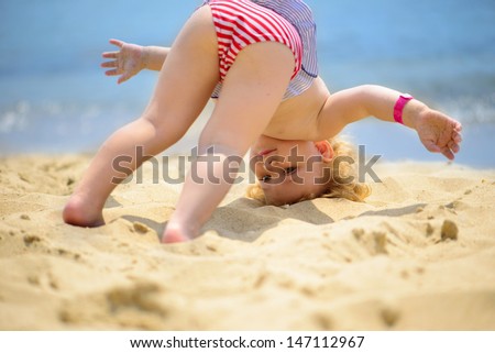 Cute little baby girl making yoga exercises at ocean beach Cute little baby girl making yoga exercises at ocean beach