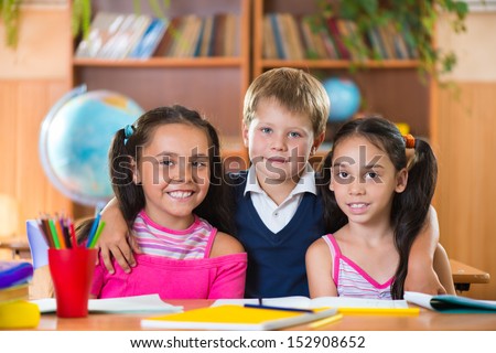 Portrait of smart schoolchildren looking at camera in classroom