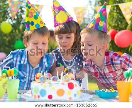 Kids celebrating birthday party and blowing candles on cake Kids celebrating birthday party and blowing candles on cake
