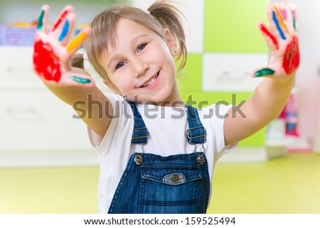 Portrait of happy little girl with colorful pains on hands