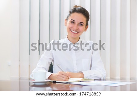 Beautiful young woman in white sitting at the table