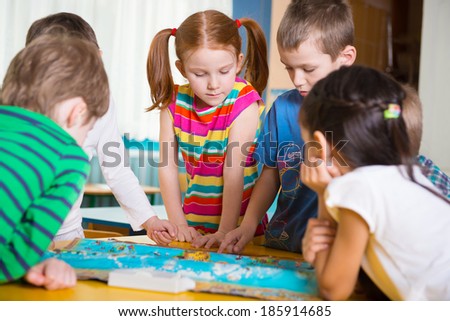 Cute preschoolers playing geography game on table