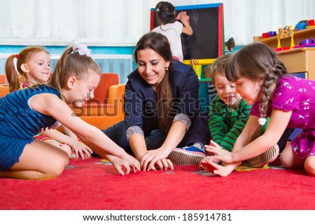 Children with tutor playing development games at kindergarten