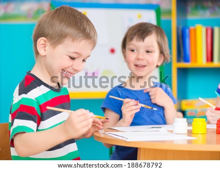 Cute little preschool children drawing with colorful paints at kindergarten