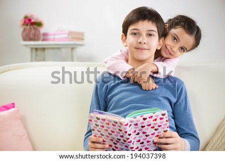 Brother and cute little sister reading book at home