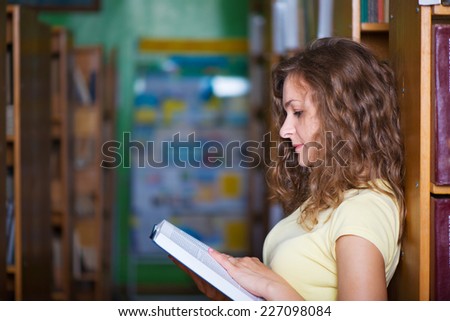 Portrait of clever student with books in college library