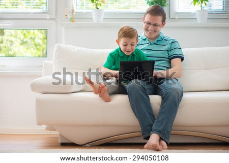 Happy father and child playing with laptop at home
