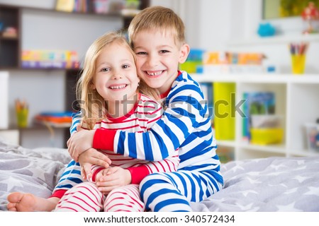 Cute little brother and sister in pajamas at home