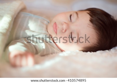 Closeup portrait of sleeping baby covered with knitted blanket