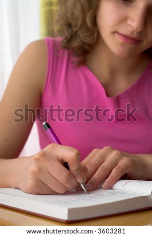 Young female is writing notes and planning her schedule.