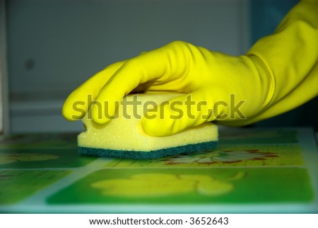 Young woman in muffles is washing table.