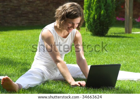 Shoeless student with laptop on campus lawn