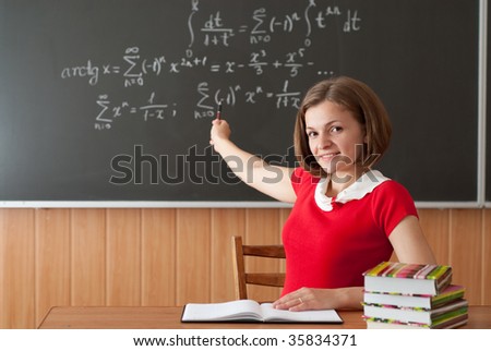 Young teacher is pointing on blackboard with math formulas