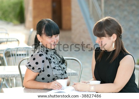 Two friends having coffee break in street cafe