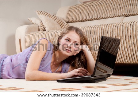 Young blonde woman is lying on the floor with laptop