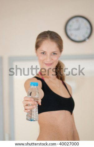 Young girl after fitness workout. Primary focus is on bottle of water