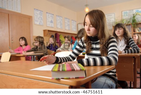 Cute schoolgirl is making notes during lesson