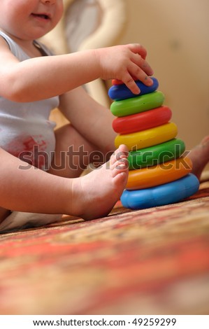 Little boy is playing with toy pyramid