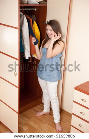 Young girl is making clothes choice near wardrobe