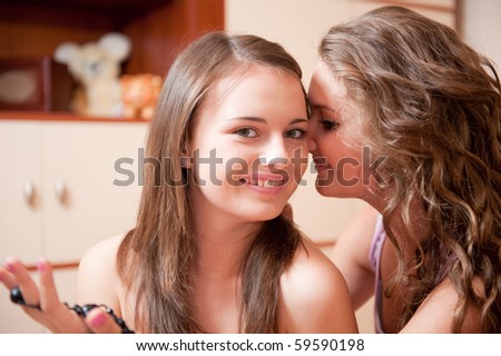 Young girl whispering a secret to her friend