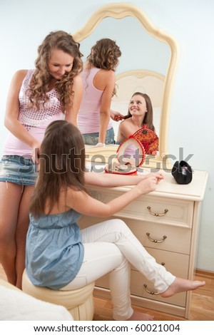 Two young girls near mirror in bedroom
