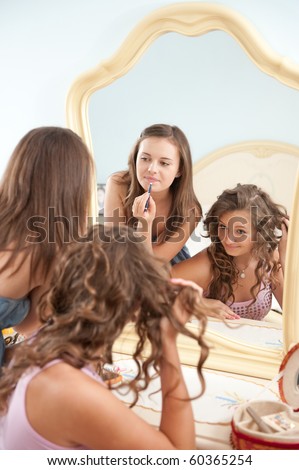 Two young girls near mirror during make-up