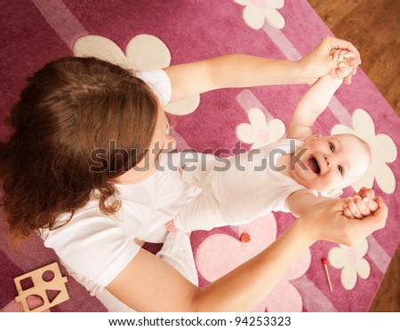 Young mother is helping her daughter to make first steps
