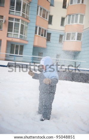 Little boy aged 2 playing with snow in the yard