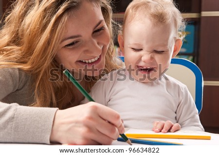 Young mother and her baby daughter drawing with pencils