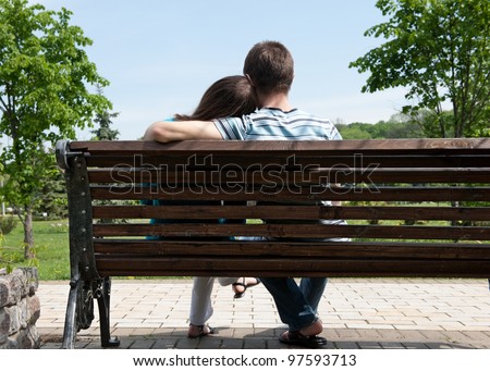 Young couple sitting on bench in park. Rear view.
