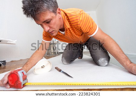 Repairs in the apartment. Man glues wallpaper in the room.