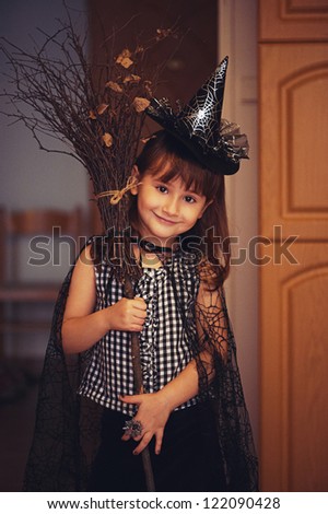 Portrait of adorable little witch with broom. Halloween costume. With some grain