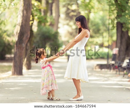 Mother and little daughter having fun in a park on a nice sunny day.
