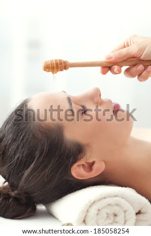 Woman having honey facial massage at spa salon