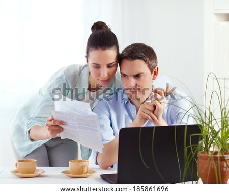 Portrait of happy couple online banking using laptop and credit card