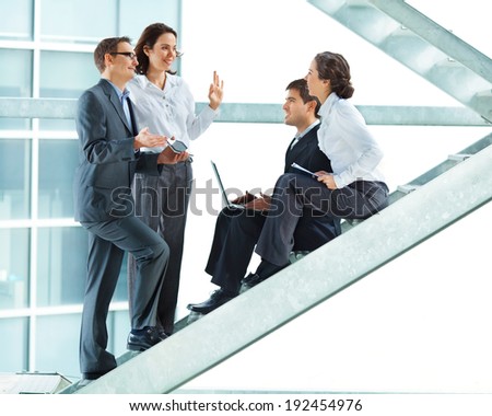 Group of four business people having a conversation in the office building.