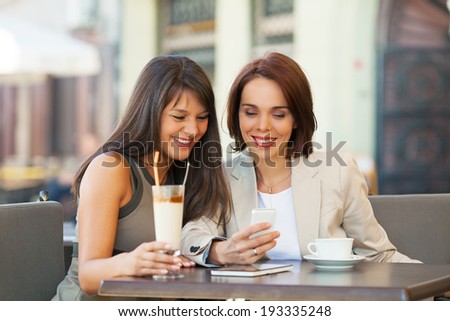 Two businesswomen sitting in a cafe and having a conversation