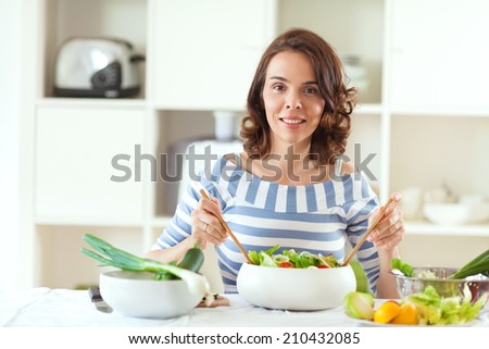 Woman is making salad in her kitchen