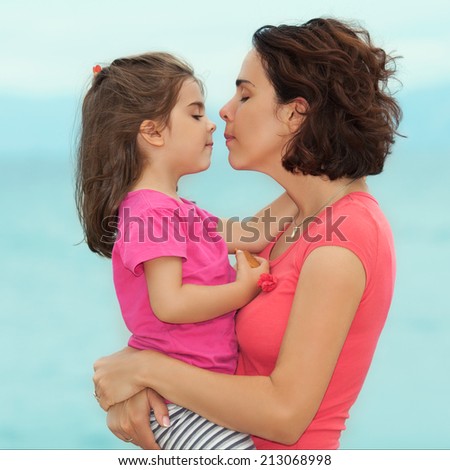 Portrait of mother and daughter kissing by the seaside
