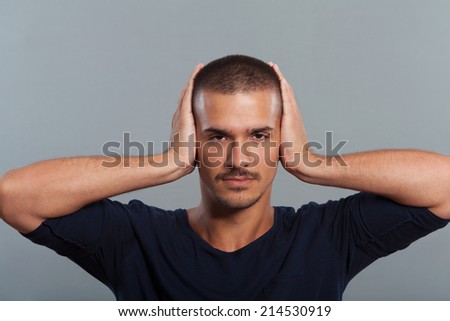 Young man covers ears with hands.