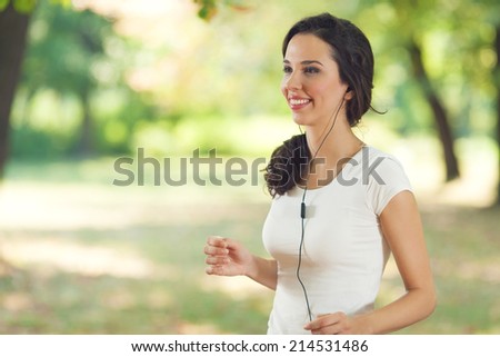 Young woman exercising in a park with headphones in her ears.
