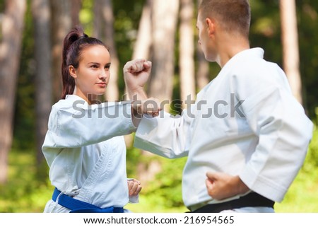 Young woman doing Gyaku-tsuki exercise with her instructor of Martial Arts