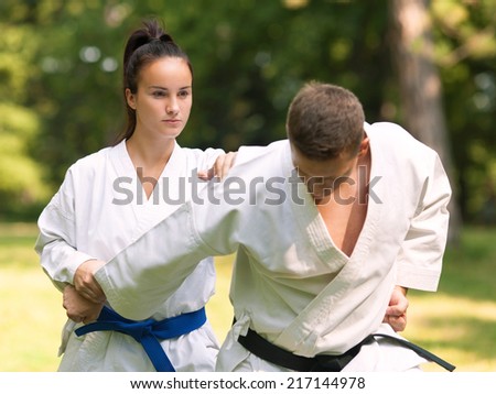 Young woman and man practicing karate outdoors