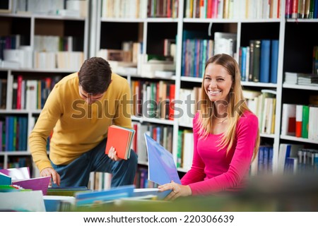 Couple of college students looking for a book in the library.